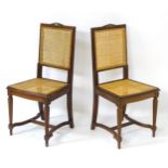 A pair of early 20thC mahogany chairs with caned backrest and seat,