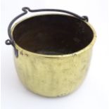 A 19thC brass cooking pot with wrought iron swing over handle.