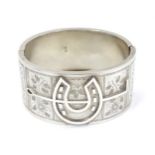 A Victorian silver cuff bracelet of bangle form with horseshoe and floral decoration.