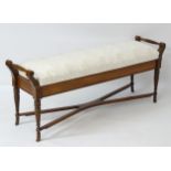 An early 20thC mahogany window seat with turned handles to each side with carved floral decoration,