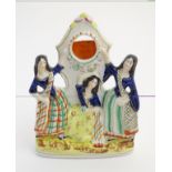 A Victorian Staffordshire pottery pocket watch holder formed as a flatback figural group depicting