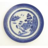 A Chinese blue and white hand painted willow pattern plate. Approx. 9 1/2" diameter.