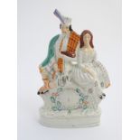 A Victorian Staffordshire pottery flatback figural group of a man and a woman seated above a clock
