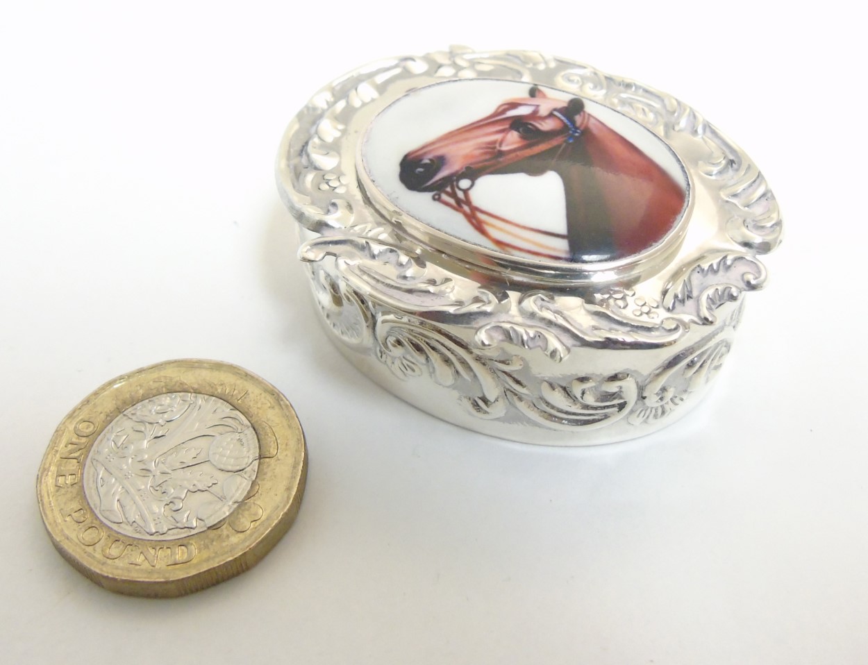 A pill box of ovoid form having enamel cabochon to lid, depicting a horses head,