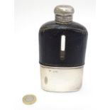 A glass hip flask with half leather covering and silver beaker to lower half,