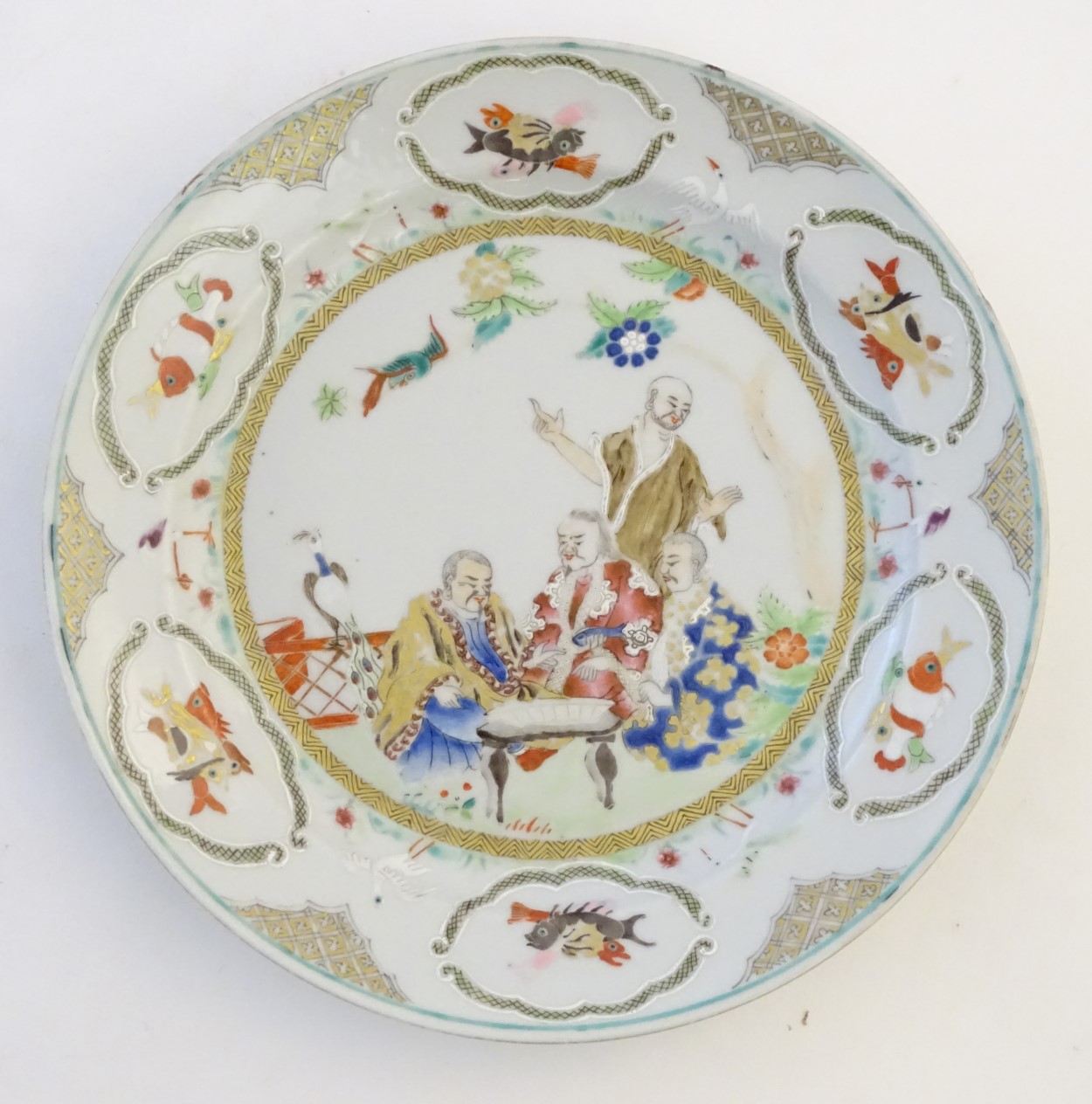 A Chinese famille verte plate with gilt highlights, decorated with four figures in a garden,