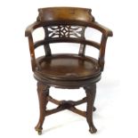 A mid 19thC mahogany captains chair with pierced back rest and revolving saddle seat,