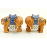 A pair of Chinese ceramic elephants with rust coloured bodies and blue and white patterned saddles.
