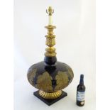 A large black glass and gilt ornamented table lamp of bottle form with gilt top and surmounted by a