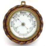 Aneroid Barometer: a circular oak cased barometer having rope twist decoration and white dial,