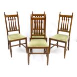 A set of four oak Arts and Crafts dining chairs with finial terminals, slatted back rests,