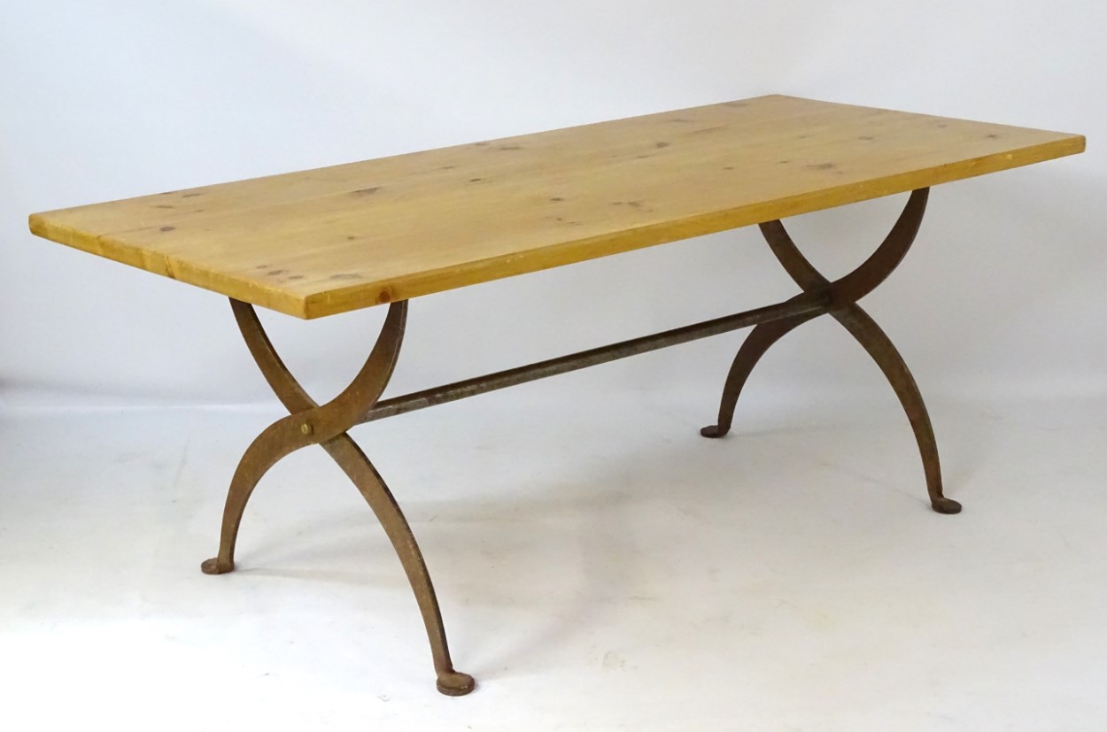A late 20thC pine topped dining table with a wrought iron X-framed base having a central trestle