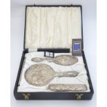 A cased dressing table set comprising brushes and mirror with embossed decoration hallmarked