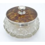 A large glass powder bowl of circular form with silver mounted faux tortoishell lid,