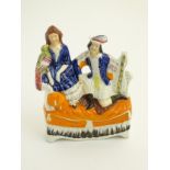 A Victorian Staffordshire pottery flatback figural group depicting a lady and a gentleman seated on