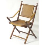 A late 19thC mahogany folding campaign chair, with leather seat, backrest and brass adorned frame.