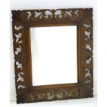 A Victorian oak mirror with a carved pierced surround depicting flowers in blossom and leaves.