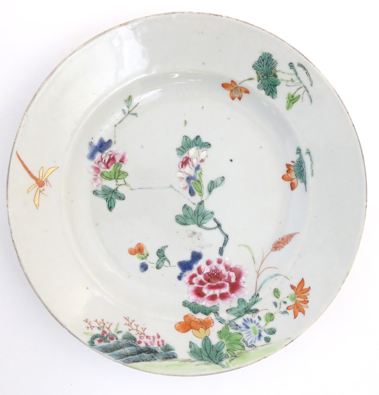 A Chinese plate decorated with flowers, a dragonfly and a rocky outcrop. Approx. 8 3/4" diameter.