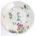 A Chinese plate decorated with flowers, a dragonfly and a rocky outcrop. Approx. 8 3/4" diameter.