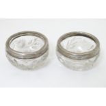 A pair of cut glass salts with silver rims,