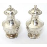 A pair of silver pepperettes hallmarked 1907 maker Goldsmiths & Silversmnmiths Co Ltd.