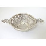 A Victorian silver strainer with pierced decoration and twin handles .