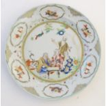 A Chinese famille verte plate with gilt highlights, decorated with four figures in a garden,