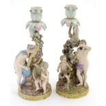 Two Meissen porcelain candlesticks, one depicting Bacchus and a child with vines and grapes,