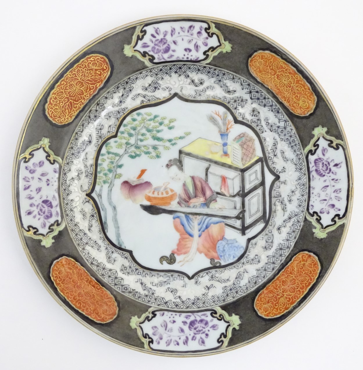 An 18thC Chinese plate decorated with a central panel depicting a lady playing a guqin instrument,