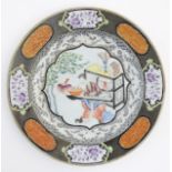 An 18thC Chinese plate decorated with a central panel depicting a lady playing a guqin instrument,