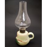 A small glass oil lamp with floral decoration, loop handle and clear glass chimney.