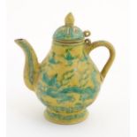 A small Chinese yellow and green teapot decorated with dragons, clouds and scrolling patterns.