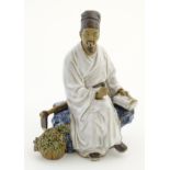 A Chinese partially glazed ceramic mudman figurine depicting a scholar/scribe,