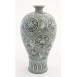 A Korean celadon vase decorated with cranes, clouds and flowers in roundels.