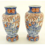 Two Imari vases decorated with an Oriental landscape, depicting flowers, trees and a garden screen,