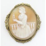 A 19thC shell carved cameo brooch depicting a lady on a terrace holding a flower.