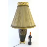 An early 20thC ceramic electric table lamp with ormolu and hand painted decoration including sirens,