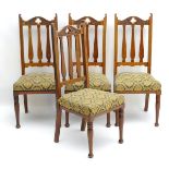 A set of four early 20thC Art Nouveau walnut dining chairs with carved cresting rails and tapering