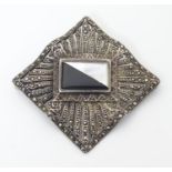 A silver brooch set with a profusion of marcasite decoration and with central black and mother of