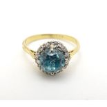 An early - mid 20thC 18ct gold ring set with central blue topaz bordered by diamonds