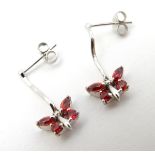 A pair of 9ct white gold drop earrings set with red spinel in a butterfly setting.