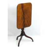 An early 19thC mahogany tripod table with a turned tapering stem, rectangular flame mahogany top,