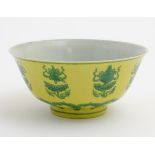 A Chinese bowl decorated with green auspicious motifs above scrolling lotus flowers on a yellow