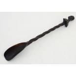 A carved ebony shoe-horn with barley twist shaft and surmounted by a tribal figure. 20" long.