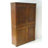 An early 19thC oak cabinet with a moulded cornice above two tiers of cupboards with panelled doors