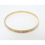 A 9ct gold bangle bracelet with engraved decoration (7.