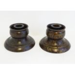 A pair of unusual Chinese cast bronze candlesticks with patinated decoration and of circular form,