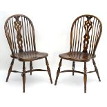 A pair of early 20thC Windsor chairs with a wheelback and pierced central splat above a saddle seat