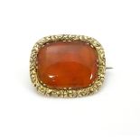 A 19thC brooch set with central carnelian within an engraved yellow metal mount.