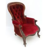 A Victorian mahogany lounge chair with button back upholstery and carved frame.